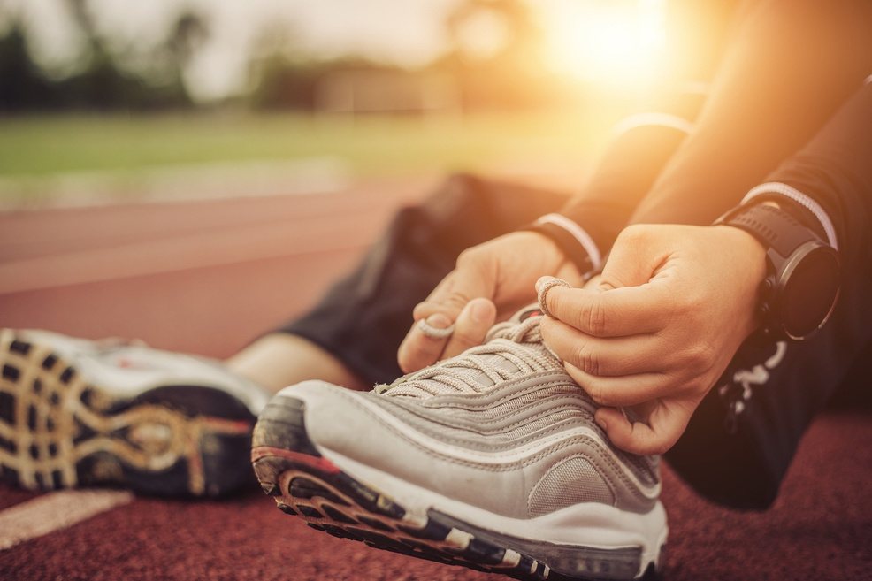 An athlete tying running shoes on a track